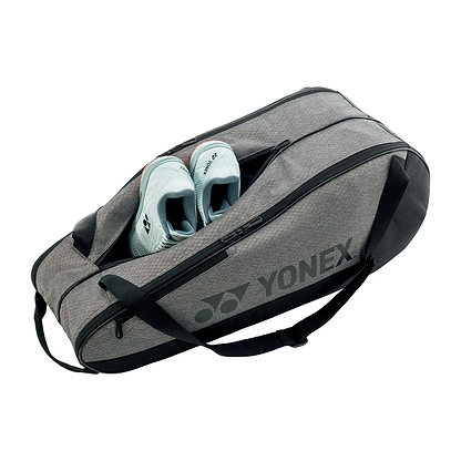 A partially unzipped Yonex 42526EX Team 6 Badminton Bag in grey with black accents reveals light blue athletic shoes inside. Designed for sports gear, it offers two handles and a shoulder strap.