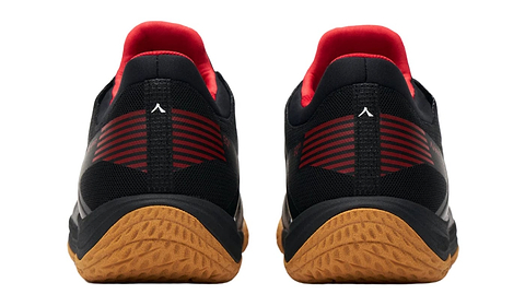 The Kanso Equilibrium EQx3 Unisex Badminton Shoes in black feature brown soles, red ankle lining, and striped red heel accents. Enhanced with Speedlight foam for comfort, these sneakers are elegantly displayed on a light neutral background.