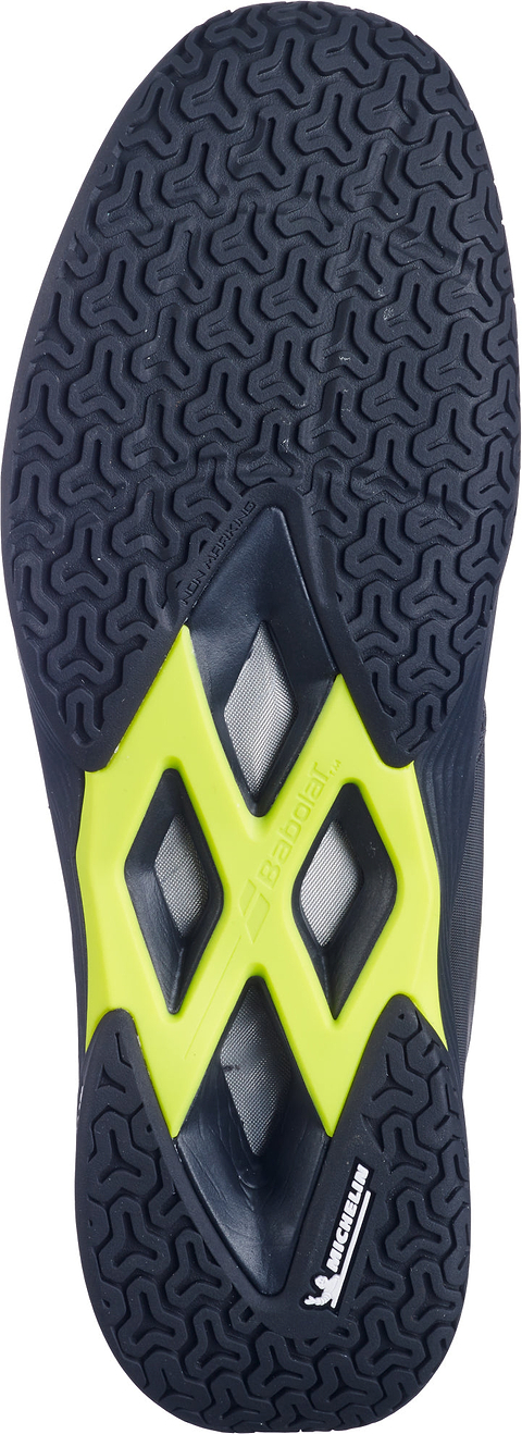 The Babolat Shadow Team 2 Mens Badminton Shoes - Black / Lime are designed specifically for indoor courts, featuring a black textured sole with vibrant lime accents at the center and prominent Babolat and Michelin logos. Their durable Michelin outsole ensures enhanced grip and performance for badminton players.