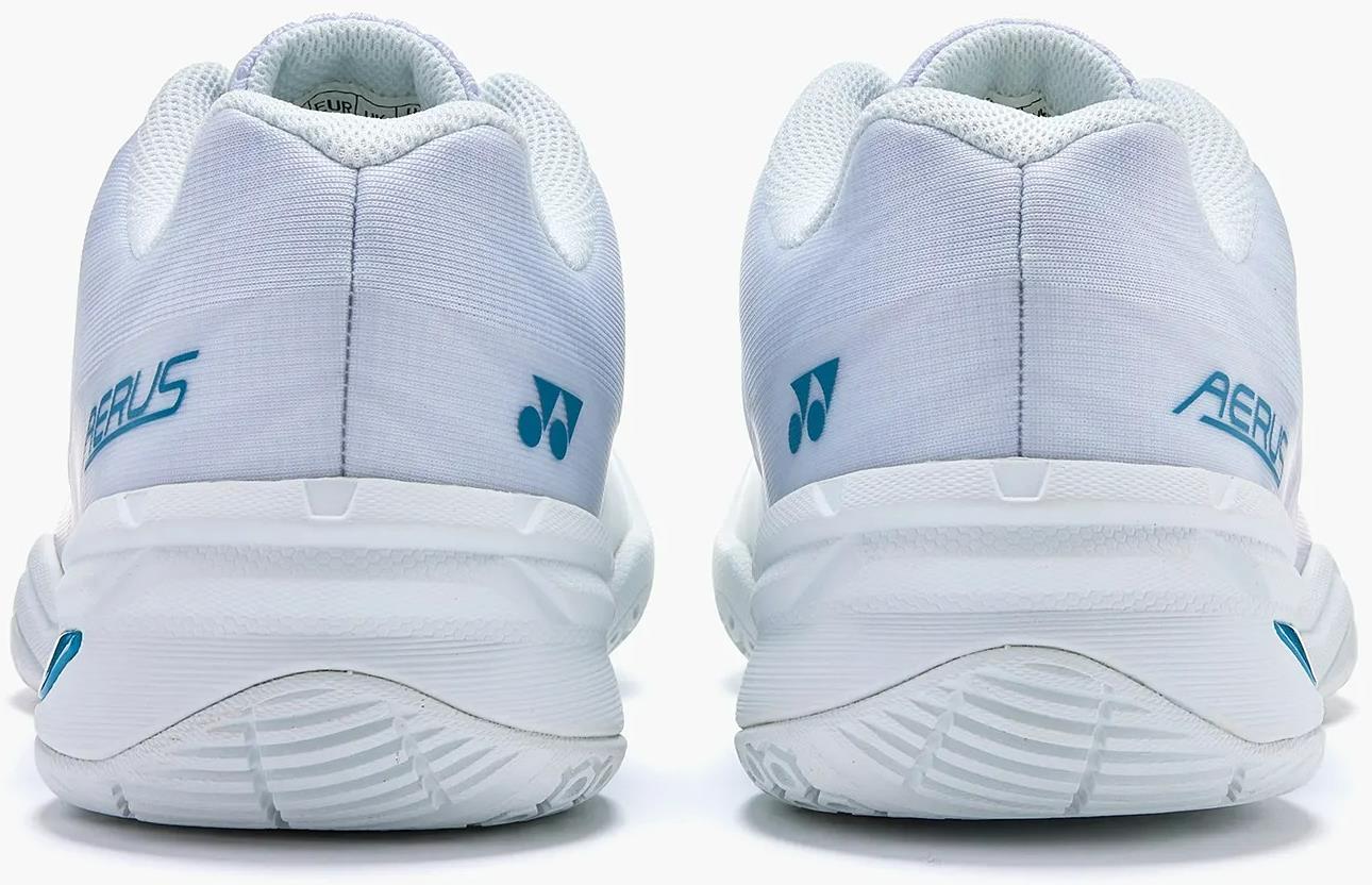 The Yonex Power Cushion Aerus X2 Unisex Badminton Shoes in White/Blue feature light blue branding and textured soles, shown from the back. These lightweight indoor court shoes offer a clean design with minimal detailing.