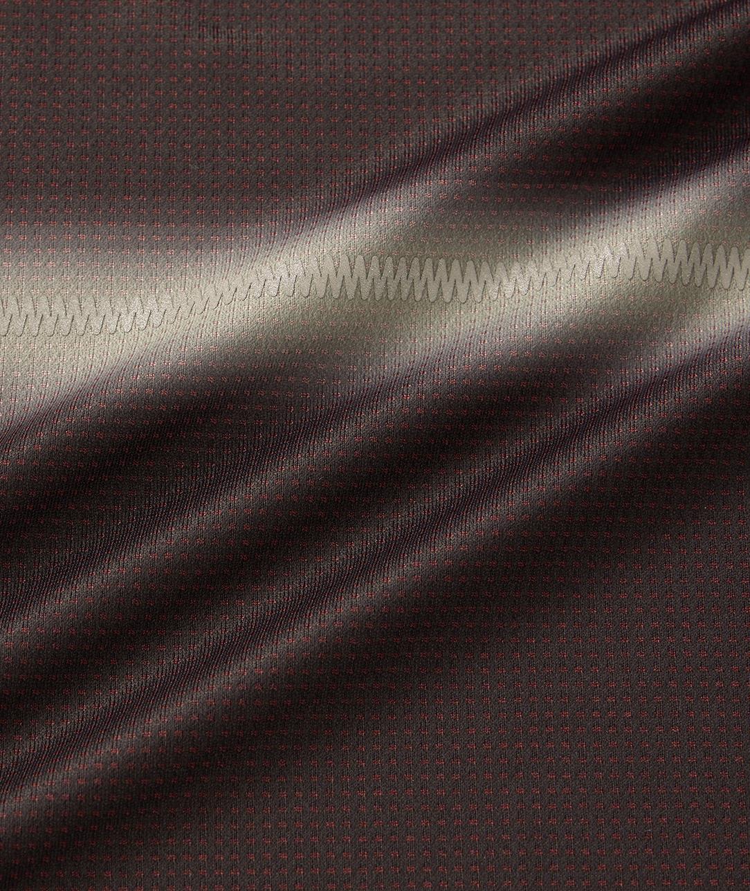 Close-up of black fabric from the Yonex 10711YX Crew Neck Men's Badminton T-Shirt, showing a subtle dotted pattern and horizontal zigzag stitching, which highlights the texture and sheen under light.