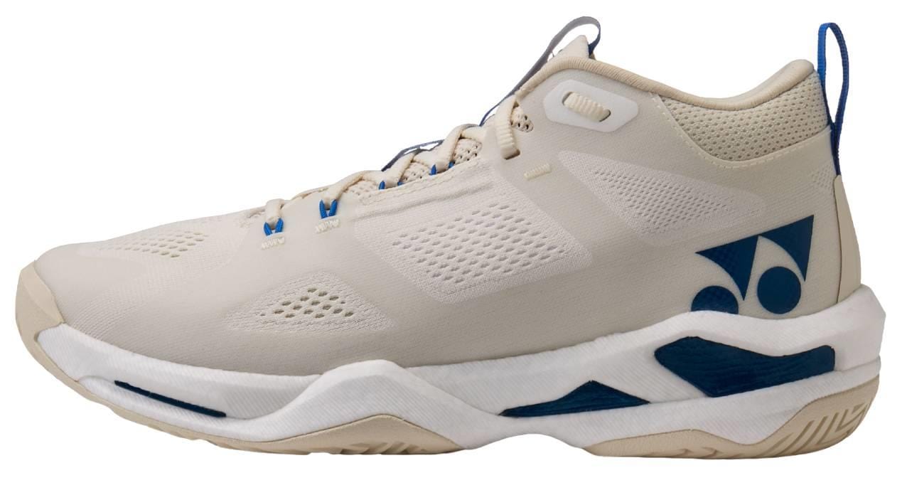 The Yonex Power Cushion GRPHT THRTTL Concept men's badminton shoe in beige has blue accents, a breathable mesh upper, a cushioned Yonex Power Cushion sole, and sports a blue Yonex logo on the side.