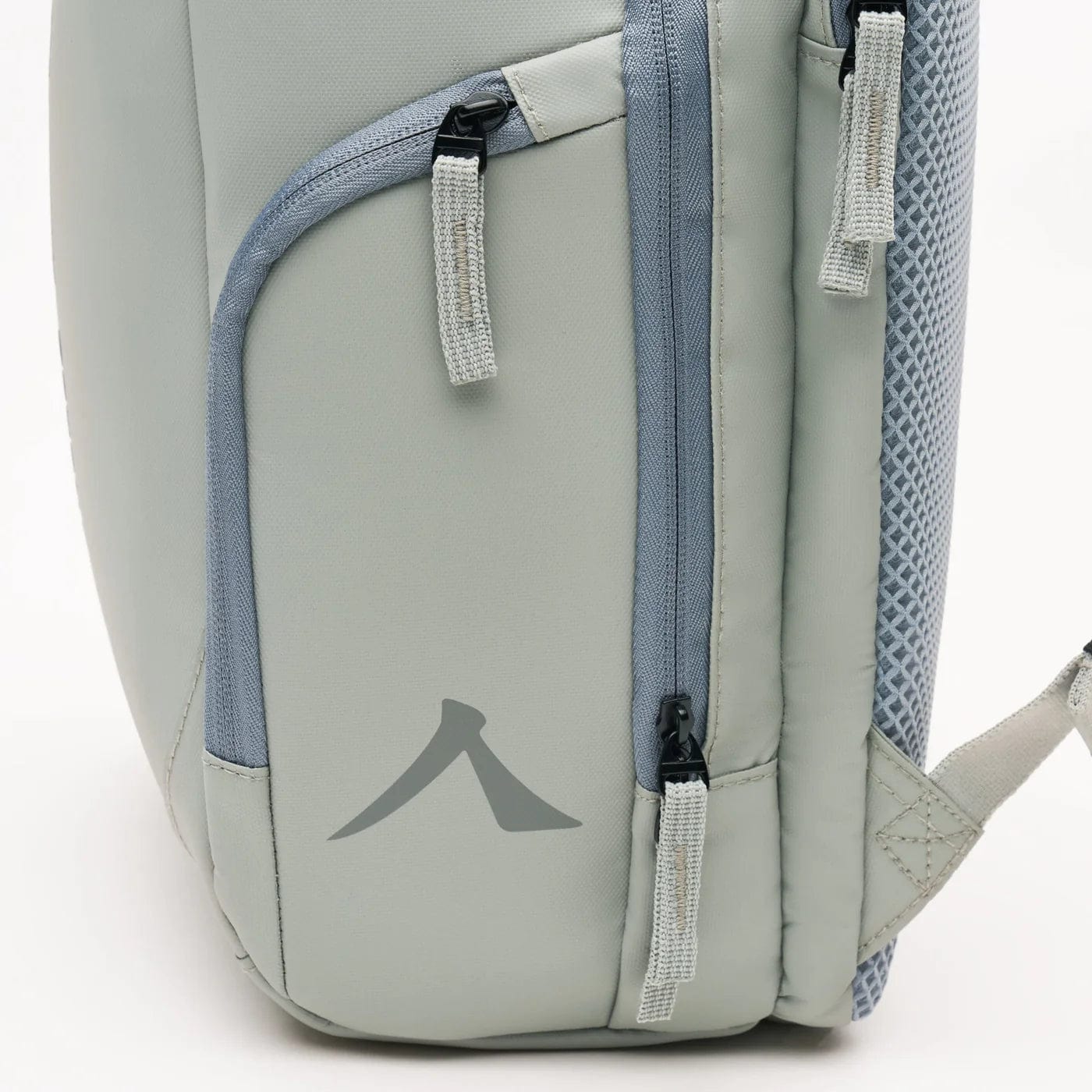 Close-up of the Kanso Intuko Badminton 23L Backpack in gray, highlighting blue-gray accents and two vertical zippered pockets, with a subtle triangular Kanso logo on the lower left corner.