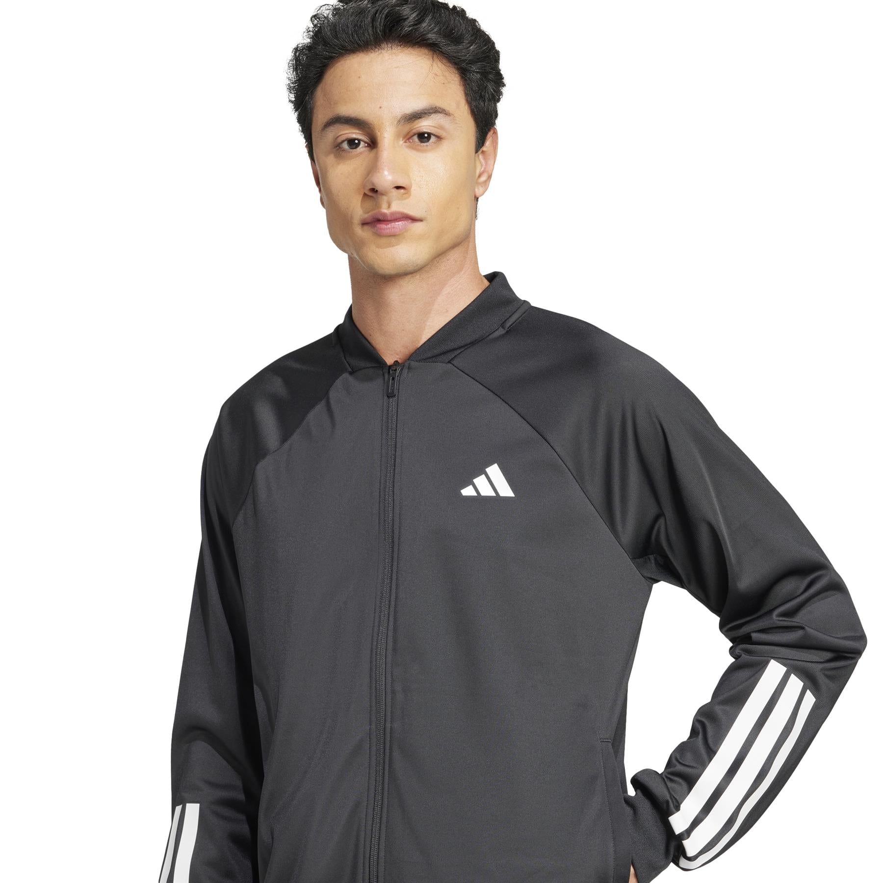 An individual with short dark hair and a calm demeanor models the adidas Men's 3 Stripe Knit Badminton Jacket in black, showcasing its iconic sleeve design and white chest logo against a plain white background, exuding sporty elegance.