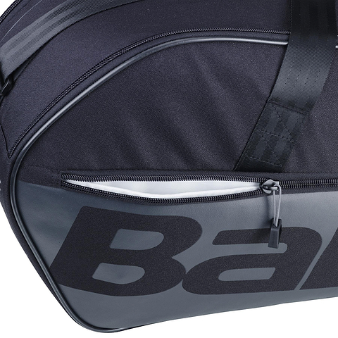 Close-up of the Babolat Court M 6 Racket Badminton Bag in black, showcasing a zippered pocket and bold lettering. Made from recycled PET, the durable fabric and prominent zip pull emphasize its sleek design.