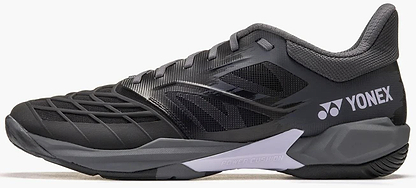 The Yonex Power Cushion Cascade Drive 3 Unisex Badminton Shoes in Black/Grey are shown from the side, featuring a textured upper, cushioned sole with Yonex Power Cushion, and the white Yonex logo near the heel.