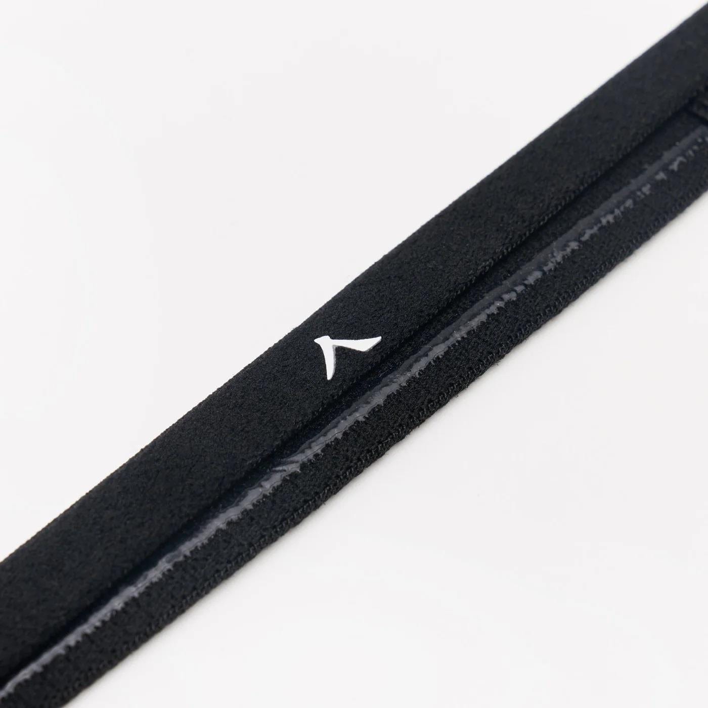 Close-up of a black textured Kanso headband featuring a small white logo, designed to keep hair away from your eyes. It's diagonally positioned against a plain white background.