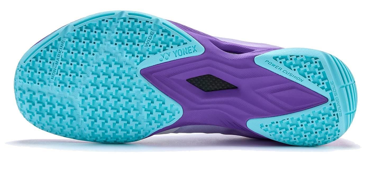 The image shows the sole of Yonex Power Cushion Aerus Z2 Wide Mens Badminton Shoes in Indigo, featuring light blue and purple textured grip patterns, with "Power Cushion" and Yonex branding designed for comfort and support.