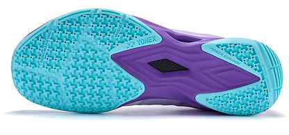 The image shows the sole of Yonex Power Cushion Aerus Z2 Wide Mens Badminton Shoes in Indigo, featuring light blue and purple textured grip patterns, with "Power Cushion" and Yonex branding designed for comfort and support.