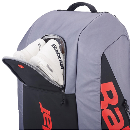 The Babolat RH9 Pure Strike 9 Racket Tennis Racket Bag in Carbon Grey features a large red “Babolat” logo, a front compartment for gear or shoes, and a water repellent finish for added protection.