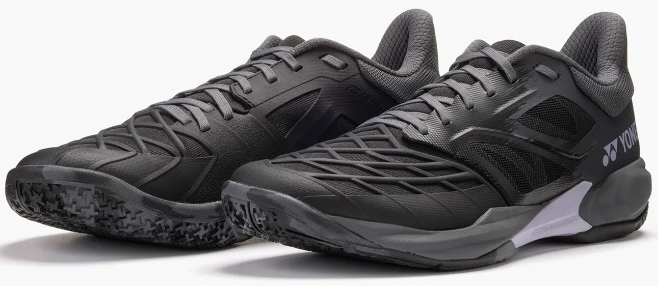The Yonex Power Cushion Cascade Drive 3 Unisex Badminton Shoes in black and grey feature mesh panels, textured soles, and a supportive modern design, shown side by side on a neutral background.