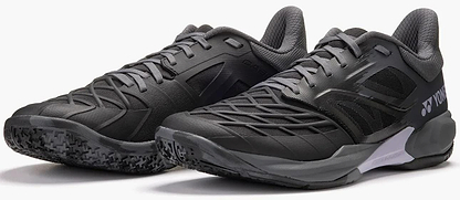 The Yonex Power Cushion Cascade Drive 3 Unisex Badminton Shoes in black and grey feature mesh panels, textured soles, and a supportive modern design, shown side by side on a neutral background.