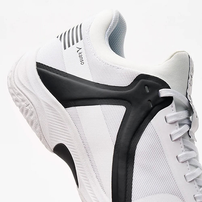 Close-up of the Kanso Equilibrium EQx3 unisex badminton shoe in white/black. It features a textured sole with shock absorption, branded "Kanso" on the side, Speedlight Foam for performance, and parallel black stripes near the top.