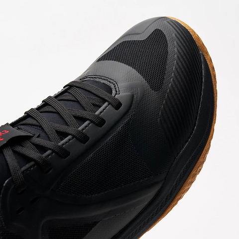 Close-up of the Kanso Equilibrium EQx3 Unisex Badminton Shoes in black, showcasing a textured mesh design. These versatile shoes feature black laces, a gum sole, and a small red logo on the tongue, standing out stylishly against the white background.