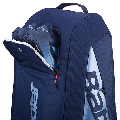 The Babolat RH12 Pure Drive Gen11 12 Racket Badminton Bag in navy blue sports a bold "Babolat" logo, with a partially open zippered compartment showcasing blue and black shoes. Designed for versatility, it has a top handle and can store badminton rackets.
