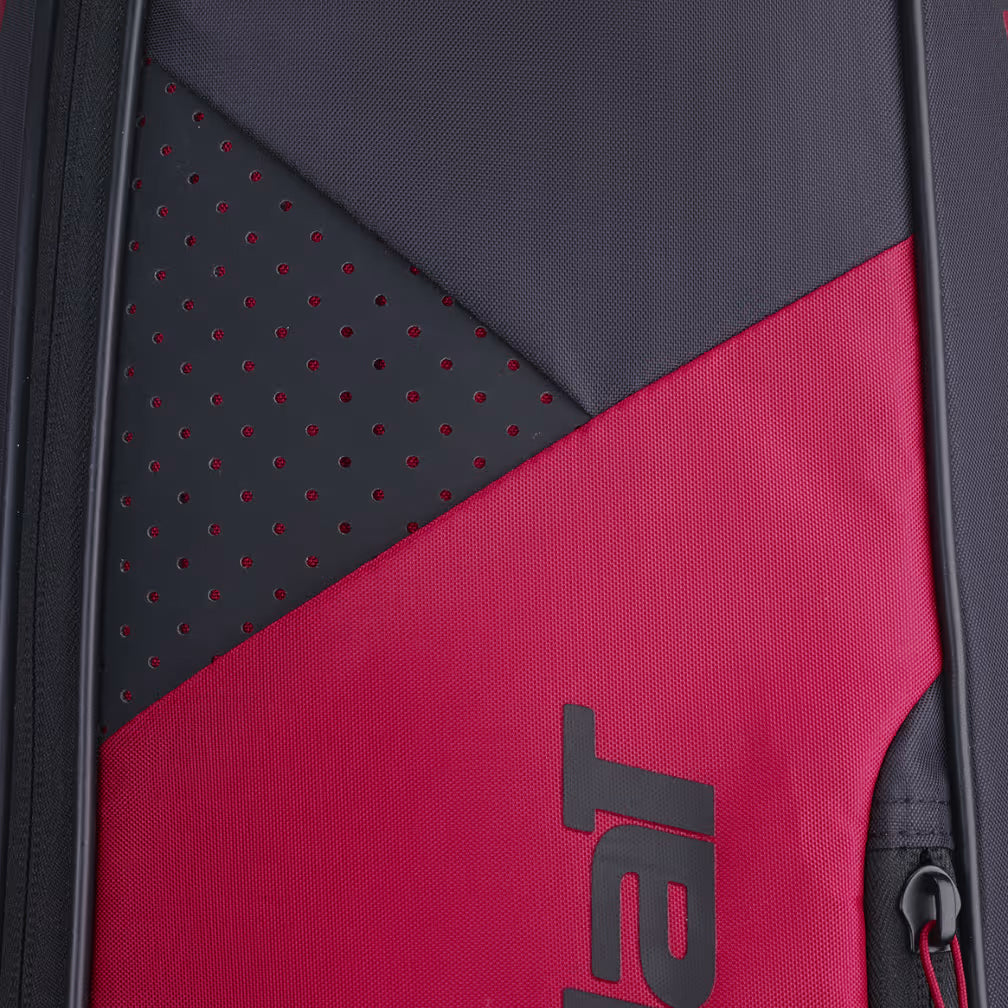 Close-up of a black and red textured Babolat Backrack 3 badminton bag, featuring small ventilation holes and a partially visible zipper. The Babolat logo is partly visible in bold letters, evoking the streamlined design of this distinctive racket backpack.