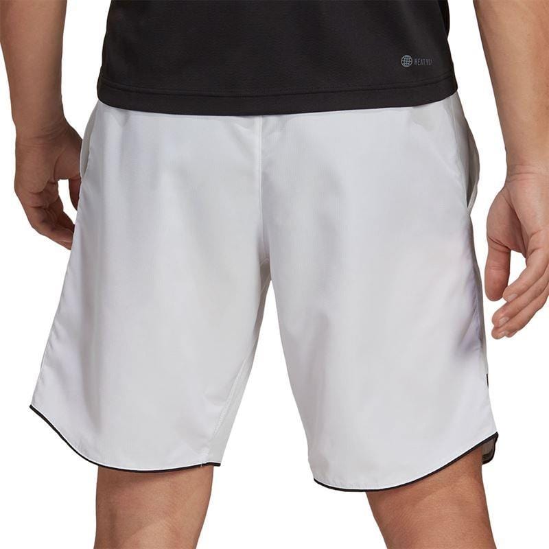 A person wearing a black shirt and ADIDAS Men's Club 7" Badminton Shorts in white stands with their back facing the camera, showcasing these badminton shorts. The focus is on the AEROREADY design, emphasizing both comfort and style.