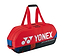 The Yonex 92431WEX Pro Tournament 6 Racket Badminton Bag in Scarlet is equipped with dual handles and a zippered top featuring durable YKK zippers. The bag prominently displays the Yonex logo along with "pro performance" text in white, complemented by sleek black and blue accents on the sides.