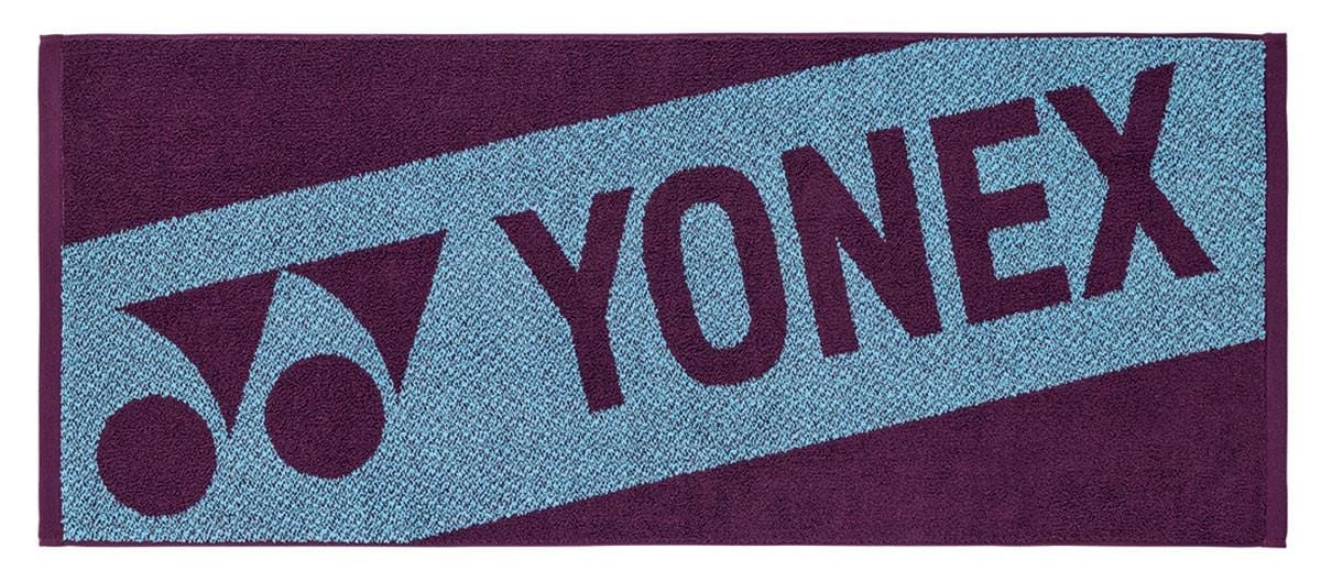 The Yonex AC1113EX Badminton Sports Towel - Bordeaux is a 100% cotton rectangular towel with a blue diagonal stripe, "YONEX," and the Yonex logo in dark purple on a contrasting purple background.