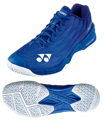 The Yonex Power Cushion Aerus X2 Unisex Badminton Shoes in navy blue are shown from the side and bottom, highlighting their white hexagonal-patterned sole with the Yonex logo, Power Cushion technology, white accents, and a lace-up design.