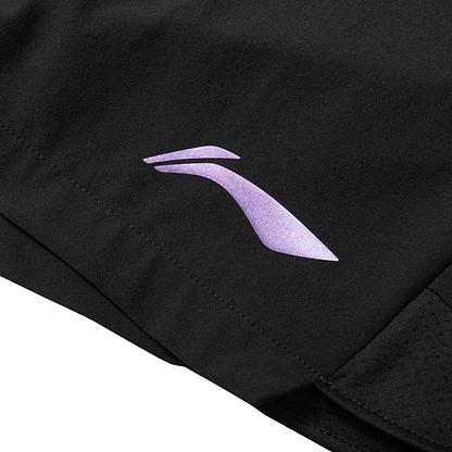 A close-up of black Li-Ning Tournament Men's Badminton Shorts shows a sleek purple logo, resembling a stylized wing or swoosh. The smooth, likely moisture-wicking fabric suggests high-performance sportswear.