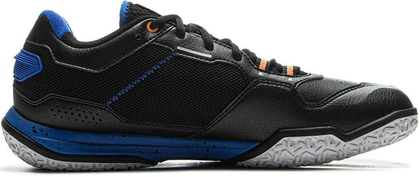The Li-Ning Saga III Lite Men's Badminton Shoe in black features blue and orange accents, mesh and leather panels, Cloud cushioning, and a white patterned rubber sole—shown in profile view with the toe pointing right.
