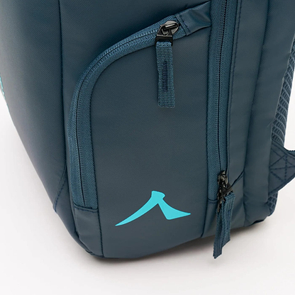 Close-up of the Kanso Intuko Badminton 23L Backpack displaying navy material with two black zippers and a turquoise logo similar to an arrow or mountain peak. The durable, smooth fabric highlights a strap partially visible in the background.