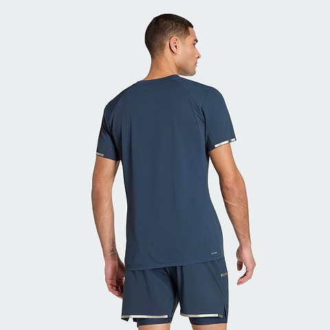 A man in an ADIDAS Climacool+ Freelift Pro Mens Badminton T-Shirt - Aurora Ink and matching shorts stands with his back to the camera, displaying the outfit’s rear view.