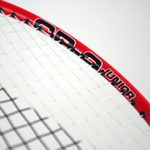 A close-up of the Karakal CB-2 2.1 Junior Badminton Racket showcases its red frame with an aluminium head and white strings, featuring "Junior" text and numeric markings in black. The focus is on the upper section of the racket set against a simple white background.