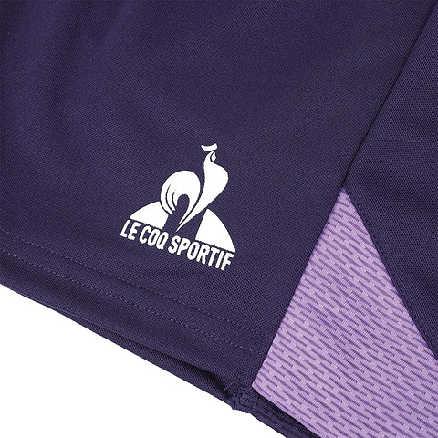 A close-up of the "Le Coq Sportif Pro Mens Badminton Shorts - Purple Velvet" showcases the brand's signature logo, featuring a white rooster and text. The breathable fabric ensures optimal movement, and its textured pattern contrasts beautifully with the smooth area displaying the logo, making these shorts ideal for badminton.