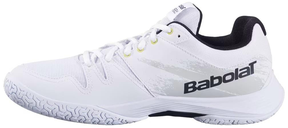 The Babolat Shadow Team 2 Men's Badminton Shoes in White feature a textured rubber sole for indoor courts, white laces, black and gray accents, and the Babolat logo on the side.