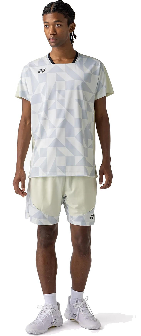 A person stands facing forward, wearing the Yonex 10712YX Crew Neck Men’s Badminton T-Shirt in Champagne with matching light geometric shorts, white socks, and white athletic shoes against a plain white background.