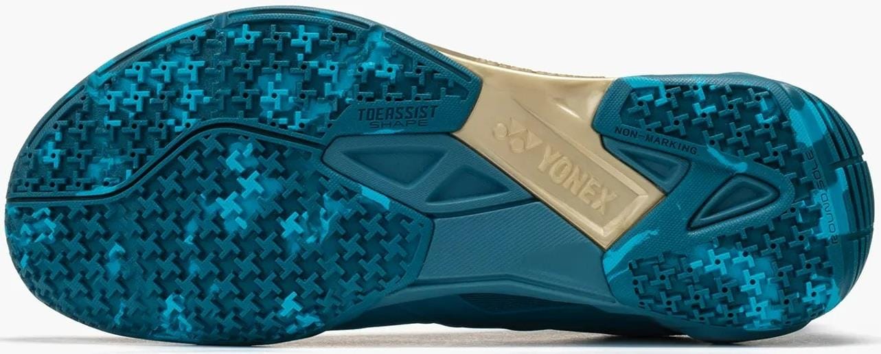 Close-up of the Yonex Power Cushion Cascade Drive 3 Unisex Badminton Shoes - Peacock Blue sole, showing blue and teal grip patterns, "NON-MARKING," "TOE ASSIST SHAPE," a beige midfoot with the Yonex logo, and branded details.