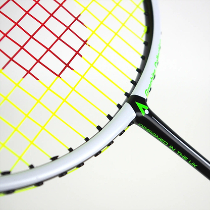 The Karakal Black Zone BZ 20 2.1 badminton racket, featuring an isometric head with a white frame and black accents, showcases red and yellow strings and the "DESIGNED IN THE UK" text on the handle. Positioned diagonally against a plain background, this high-performance racket stands out.