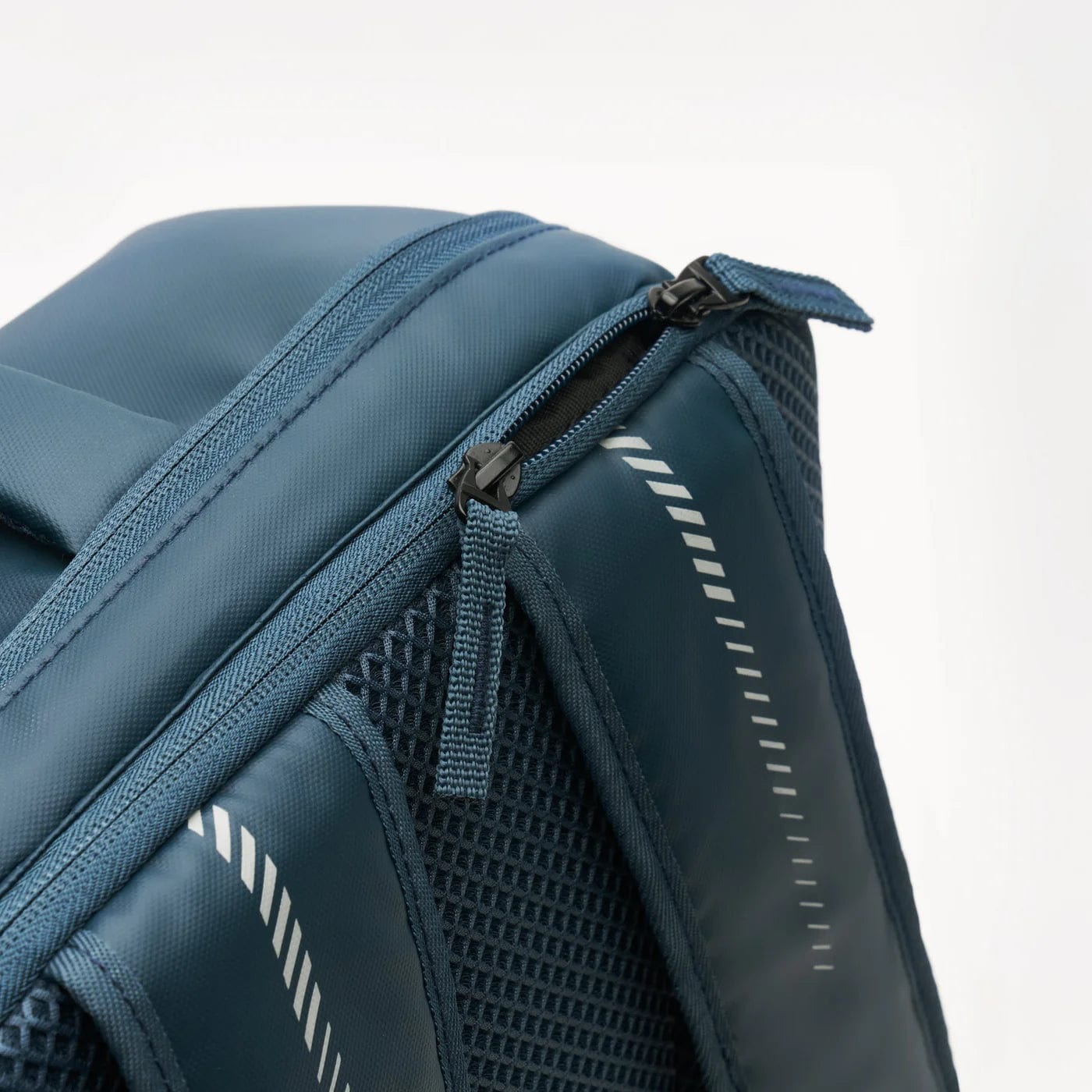Close-up of the Kanso Intuko Badminton 23L Backpack in navy, featuring a zipper opening, mesh side pockets, and diagonal reflective striped accents.