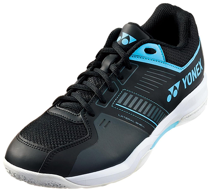 The Yonex Power Cushion Strider Flow men's wide badminton shoes in black/blue feature a laced design, breathable mesh upper, and white sole. "Yonex Power Cushion" is displayed on the side for enhanced comfort and performance.