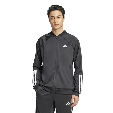 A person is wearing an ADIDAS Men's 3 Stripe Knit Badminton Jacket in black with white sleeve stripes. They stand against a plain white background with hands in their pockets.