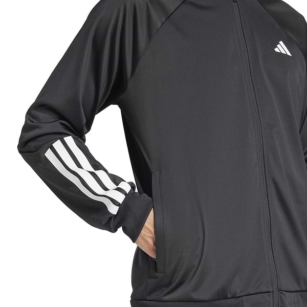 A person is wearing an ADIDAS Men's 3 Stripe Knit Badminton Jacket in black, featuring white stripes on the sleeves and a small upper chest logo, with hands tucked into pockets against a plain white background.
