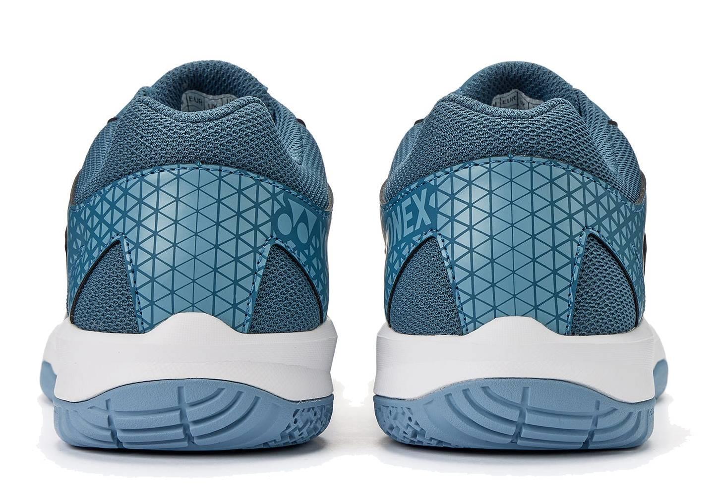 The Yonex Power Cushion Strider Ray Unisex Badminton Shoes in teal blue feature a geometric heel pattern, mesh fabric, and white soles with blue treads for superior shock absorption, inspired by the Yonex Power Cushion design.