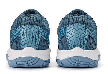 The Yonex Power Cushion Strider Ray Unisex Badminton Shoes in teal blue feature a geometric heel pattern, mesh fabric, and white soles with blue treads for superior shock absorption, inspired by the Yonex Power Cushion design.