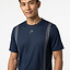 A man in a HEAD Club Tech 25 Men's Badminton T-Shirt in navy with gray stripes and a small chest logo stands against a white background, smiling slightly. This HEAD shirt features moisture-wicking fabric for breathable comfort.
