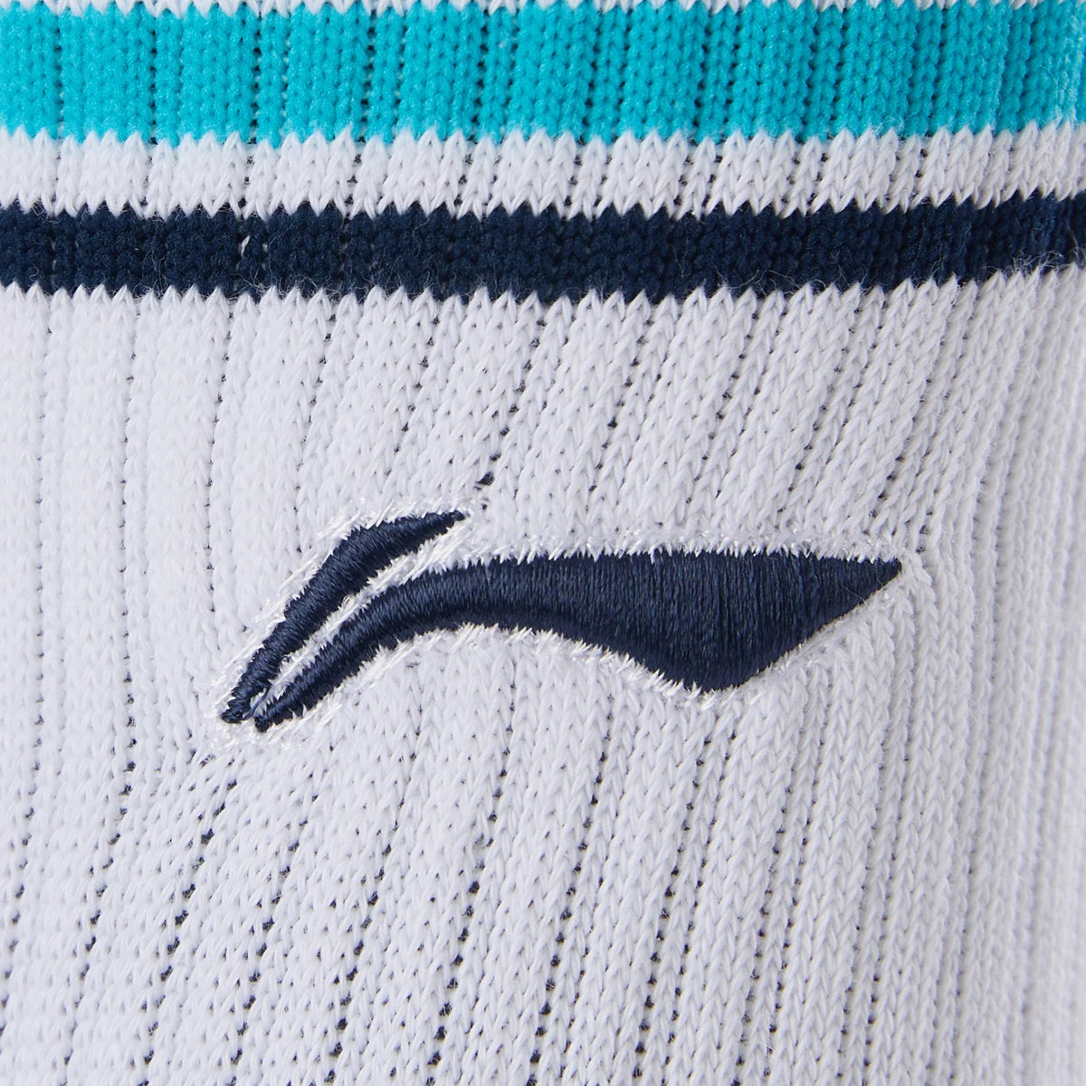 Close-up of Li-Ning Badminton Socks - White / Blue: features white ribbed fabric with blue and teal stripes, a navy embroidered logo, and moisture-wicking material for on-court comfort.