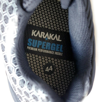 Close-up of the interior of a Karakal Super Pro Indoor Court Badminton Shoe, featuring the "Karakal Supergel Premium Performance Insole" label with a hexagonal pattern and size 44. The visible area is dark, displaying a geometric texture and an asymmetric lace system designed to enhance performance on indoor courts.