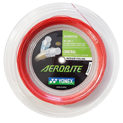 The Yonex AeroBite Badminton String in a 200m reel showcases red and white strings with "Medium Feeling" and "Control" labels, ideal for hybrid stringing. The packaging provides detailed specifications and branding in English and Japanese, designed to deliver high rotating spin for powerful shots.
