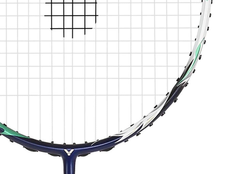 Close-up of a badminton racket head. The strings form a tight grid pattern on this Victor Auraspeed HS B Badminton Racket, showcasing part of the dark blue frame highlighted with white and green accents against a plain white background.