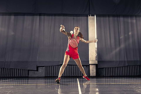 Badminton Woman Player playing a backhand shot