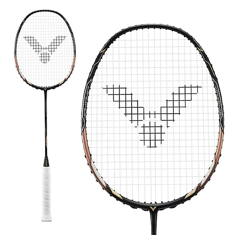 A close-up of the Victor Thruster F C Badminton Racket - Black Gold displays a unique grid pattern on the strings, housed within a sleek black and gold frame. The handle of this Victor racket is expertly wrapped in pristine white tape.