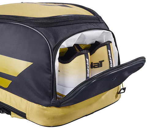A Babolat Backrack 3 Badminton Bag in black and yellow by Babolat sits with its side pocket open, showing two tennis racquet handles inside.