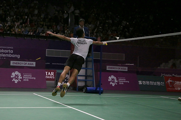 Professional badminton player playing a shot close to the net at a tournament