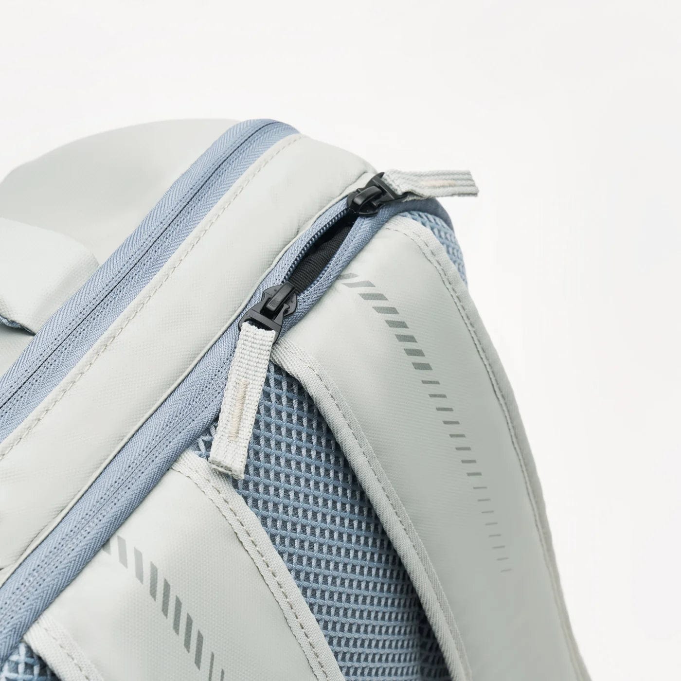 Close-up image of the Kanso Intuko Badminton 23L Backpack in gray, featuring a zippered compartment, mesh panels, and two-tone light and dark gray fabric.